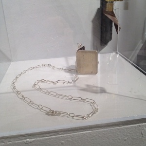 Patricia Sullivan: "Widget Locket No. 2" (installation view). Sterling silver (fabricated), fabric, archival paper, Plexiglas, handmade silver chain/hinge/clasp, 20.75" x 1.75" x .25", 2013. Photo: P.Sullivan